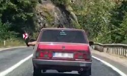 Ayaklarını camdan sarkıtarak trafiği tehlikeye attı
